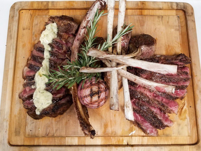 a wood board full of steak and ribs