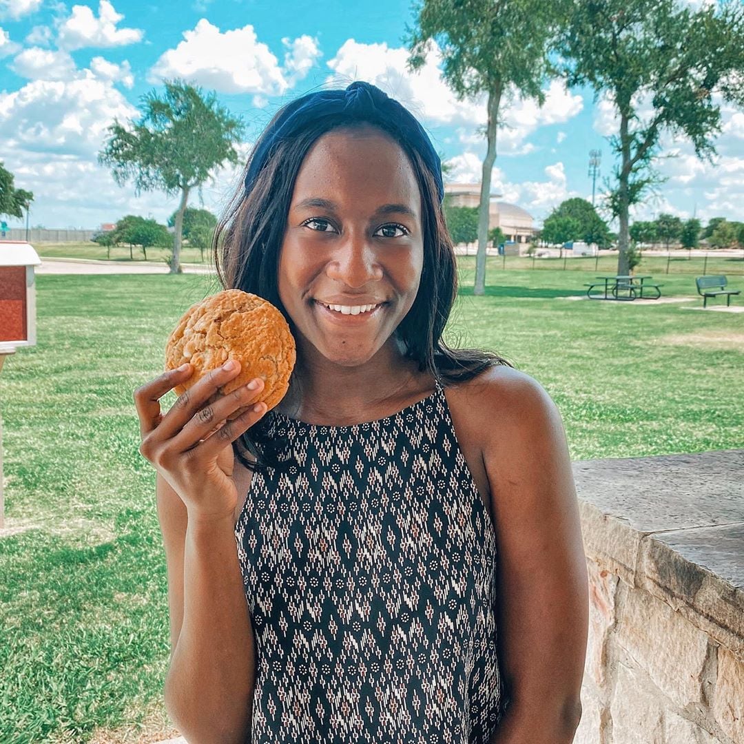 A woman holding up a cookie for Cookie Society for a photo